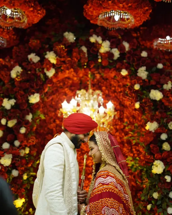 An intimate moment between the Sikh bride and groom against a wall of red flowers. This is the kind of quiet, romantic shot that tells a powerful story.