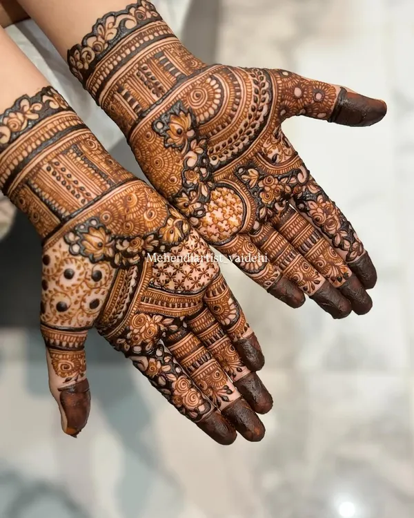 A classic full-hand bridal design with a rich, dark paste application. Notice the detailed check patterns (jaali), floral bands, and solid fingertips that create a traditional and dense look.