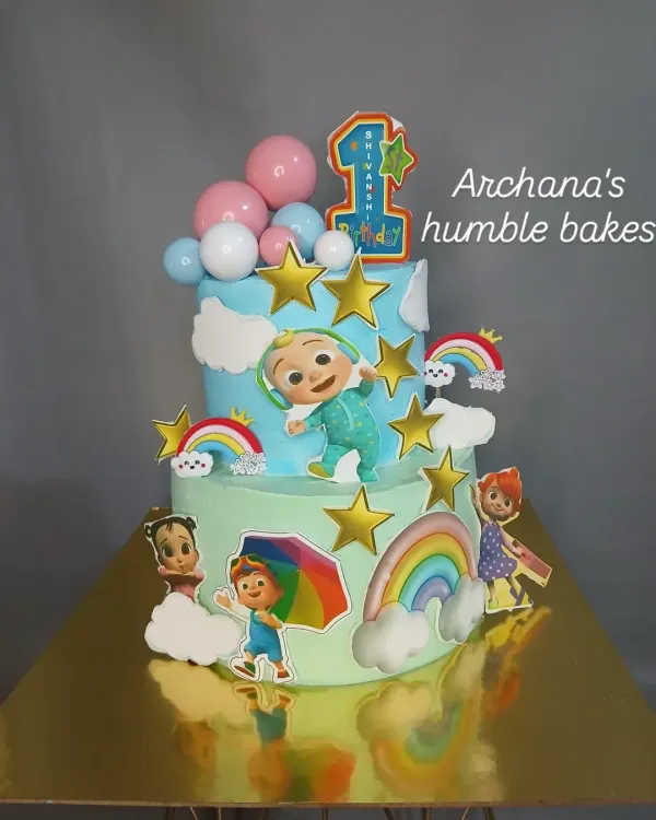 A colorful two-tier Cocomelon cake, perfect for a first birthday celebration. This design features all the beloved characters, rainbows, and stars.