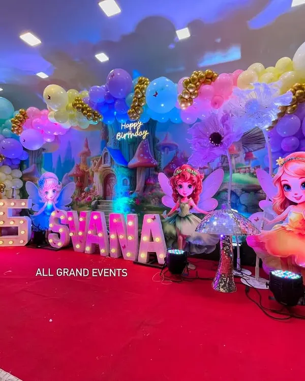 Welcome to Svana's Fairyland. This magical 5th birthday stage features a castle backdrop, large fairy cutouts, marquee letters, and a dreamy pastel balloon cloud with gold accents.