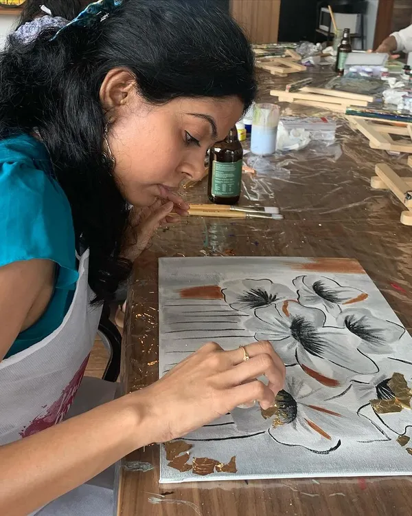 A participant carefully applies gold leaf to her floral painting. This technique adds a touch of luxury and a beautiful shimmer that makes any artwork pop.