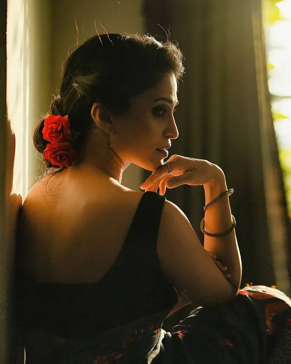 This portrait uses natural light and shadow to create a soft, romantic mood. The pose, looking back over the shoulder with flowers in her hair, has a classic elegance, while the lighting gives it a modern, cinematic feel.