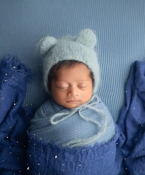 This little one is so cozy in shades of blue. A simple swaddle and a matching bear bonnet are all that's needed to create a timeless and adorable portrait.
