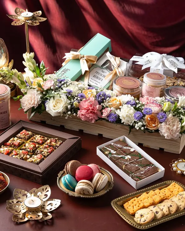 A stunning spread of my Diwali offerings, featuring a wooden crate hamper with fresh flowers, boxes of assorted cookies and macarons, and jars of treats. This showcases the variety available, from individual boxes to comprehensive gift hampers.
