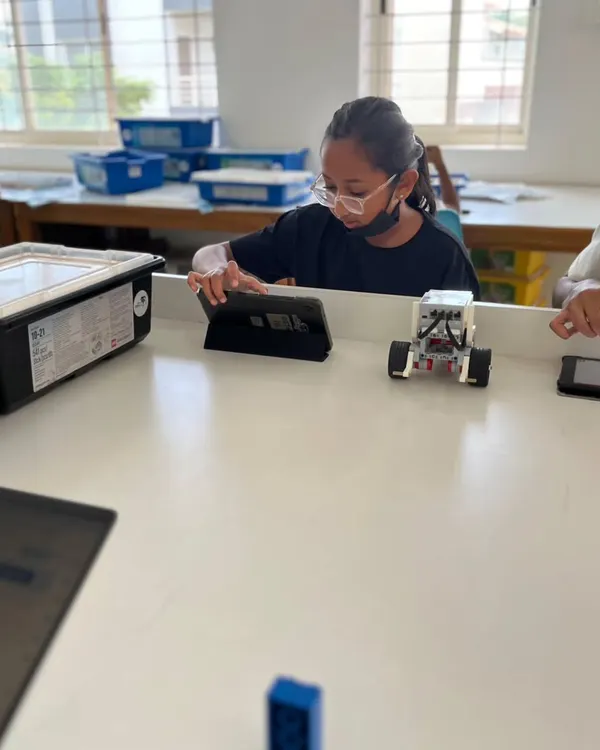 A student uses a tablet to program her robot in our well-equipped classroom. We provide the latest tools, including LEGO Education and Arduino kits, to facilitate a modern STEM learning experience.