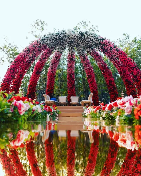 This is one of my signature designs, a grand floral dome structure for an outdoor wedding. The ombre effect using red, pink, and white flowers creates a breathtaking focal point, and the reflection in the water adds a touch of magic, perfect for a royal wedding theme.