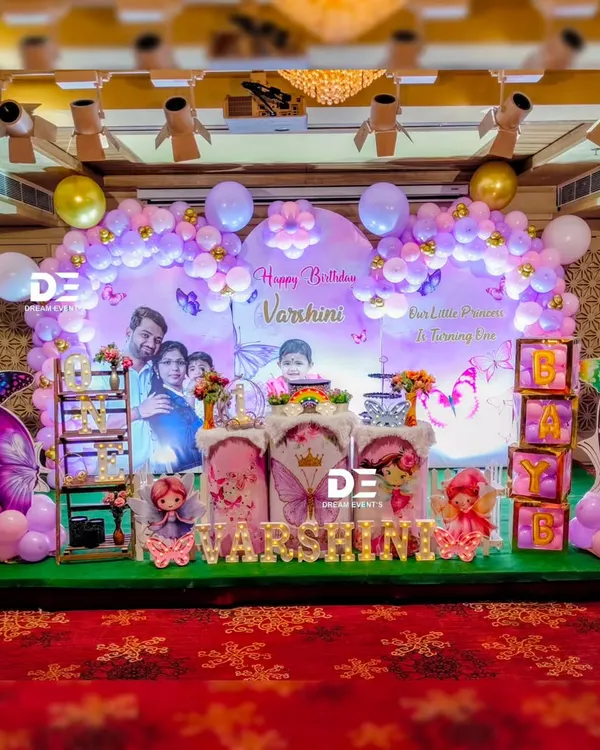A spectacular butterfly-themed first birthday stage for Varshini. I used a personalized photo backdrop, a lavender balloon arch, and large, shimmering butterfly cutouts to create this enchanting scene.