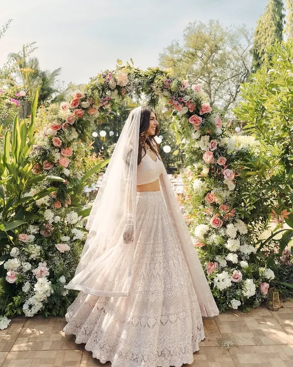 A bride stands gracefully before a lush floral archway, creating a perfect photo opportunity and a beautiful entrance to the ceremony.