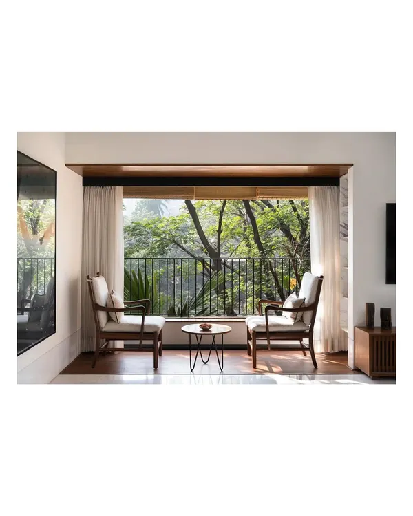 This intimate seating arrangement for two was designed to frame the lush greenery outside. I create custom armchairs like these to offer a quiet place to read or simply be, connecting the comfort of your home with the nature beyond its walls.