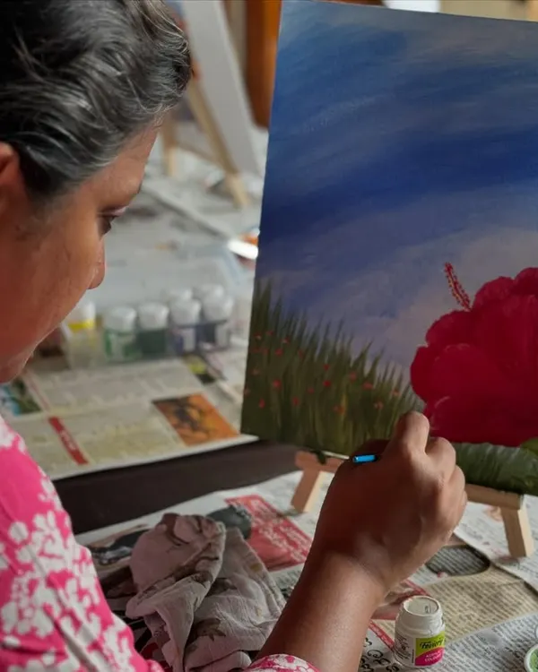 A participant lost in the moment, adding the final touches to her painting of a red hibiscus flower.