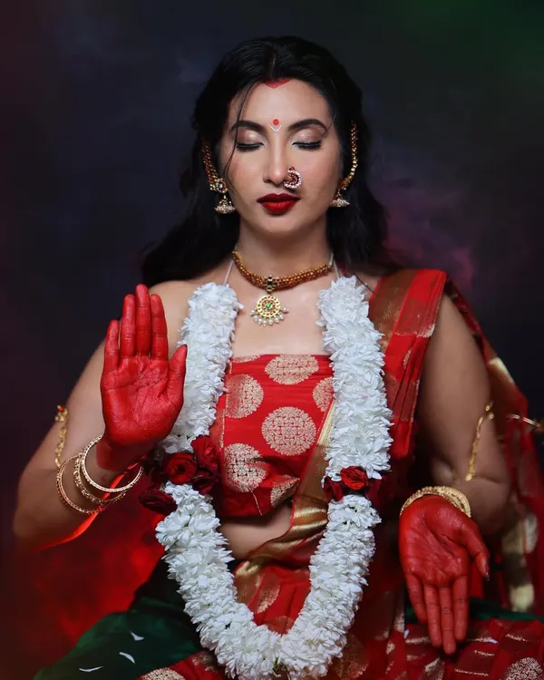 Embodying the divine feminine energy in this goddess-themed shoot. The makeup features a strong red bindi, bold red lips, and expressive eyes, complemented by traditional attire and alta on the hands.