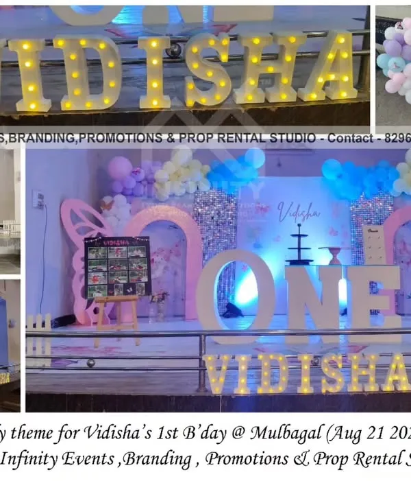 Fly like a butterfly! This magical first birthday theme in Mulbagal features a stunning sequin wall, a 3D semi-arch backdrop with butterfly wings, and a "ONE" table. The pastel balloon garland and marquee letters add to the enchanting atmosphere.