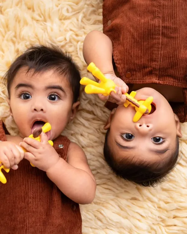 Teething time for two! This adorable shot captures twin brothers at their 6-month sitter session, each with their own teether. It's a fun way to document this milestone.