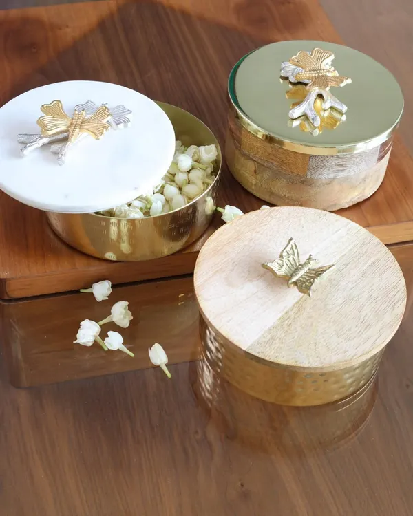 A stunning trio of our decorative keepsake boxes. This image showcases the different materials and designs we offer, from a hammered gold box with a wooden lid to a marble-lidded box with mixed-metal accents.