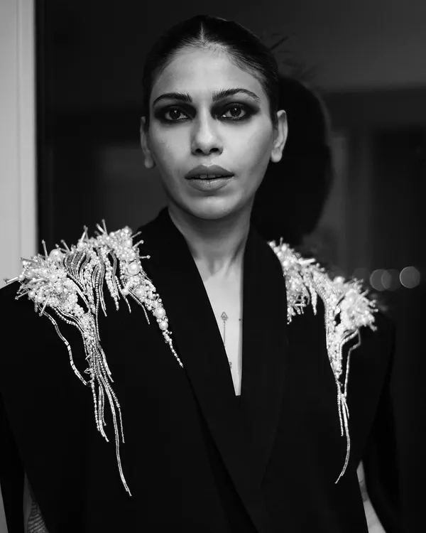 A close-up black and white portrait of Anasuya Sengupta. The focus here is on her expressive eyes and the intricate details of the Gaurav Gupta design, capturing a moment of quiet intensity.