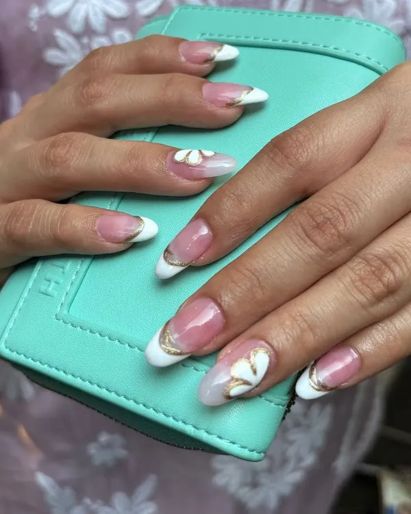 A close-up of custom nail extensions, featuring an elegant French manicure enhanced with a delicate gold chrome outline and handcrafted 3D floral art. This is the kind of detailed, glamorous look I love to create.