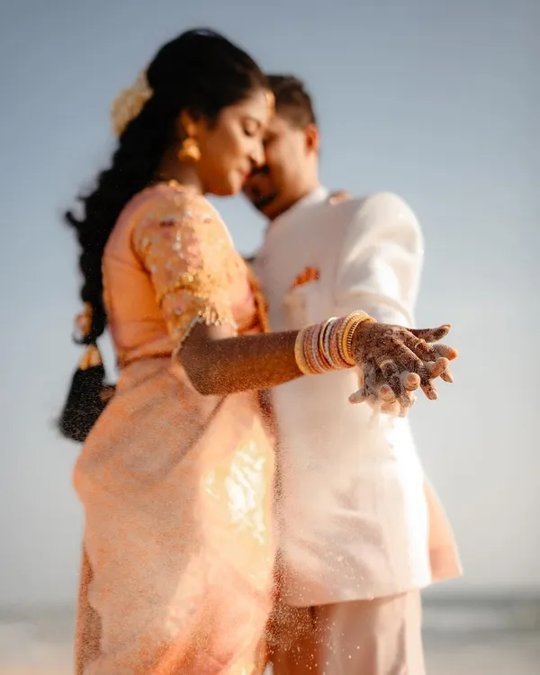 A close-up of the couple's hands, covered in sand, during their beach pre-wedding shoot. This shot focuses on the tactile details and the intimacy of their embrace by the sea.