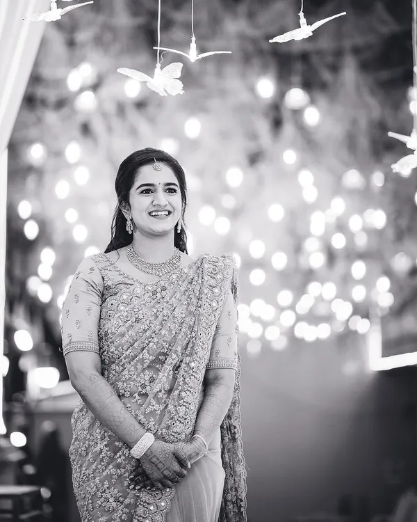 A beautiful candid portrait of the bride, her smile illuminated by the soft glow of background lights. Black and white enhances the emotion and timelessness of the moment.