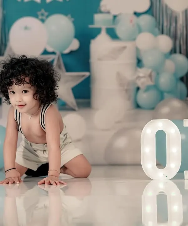 Celebrating the big ONE! This little boy is crawling towards the light-up 'ONE' sign in our beautifully decorated blue and white birthday setup.