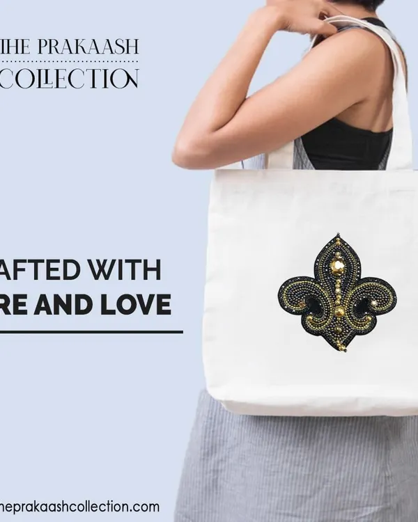 A plain white tote bag is transformed with a hand-embroidered, stone-studded fleur-de-lis patch. This shows how a simple appliqué can add a touch of character and fashionable flair to an everyday accessory.