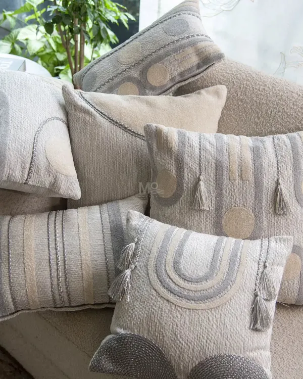 A pile of cushions from our Contours Collection, showcasing a variety of geometric designs. The soft, soothing palette and refined detailing bring sophistication to a neutral-toned sofa.