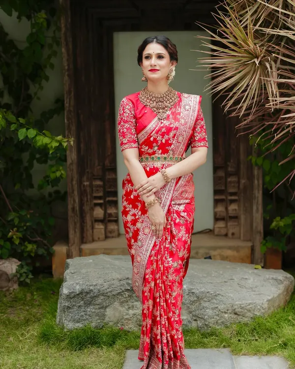 A full-length view of the pure red Katan silk Banarasi saree. The intricate handwoven floral pattern and the matching embroidered blouse create a look of unparalleled bridal grandeur.