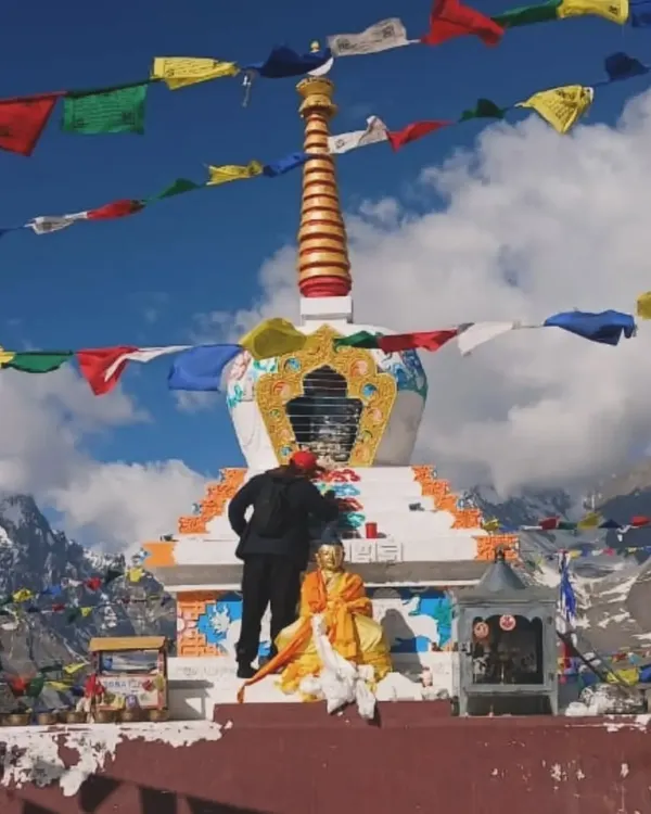 An unforgettable experience assisting a local artist to paint a Stupa at Kuncham Pass, situated 15,000 feet above sea level. This wide shot shows the scale of the stupa against the vast, snowy mountain landscape.