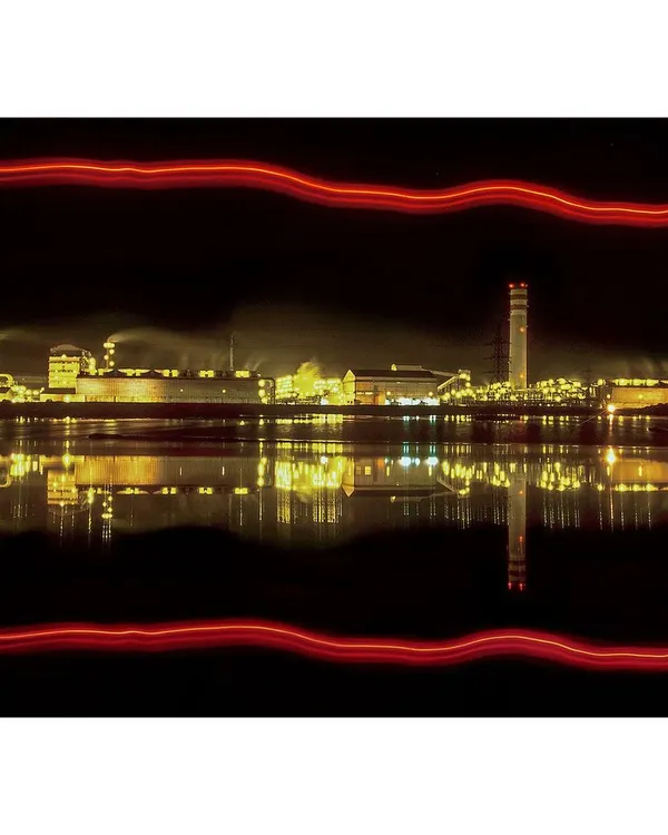 A night-time long exposure of a factory complex. The perfect reflection on the water and the creative light streaks make this a standout piece of artistic industrial photography.