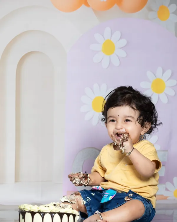 The pure joy of a first birthday cake smash! This little one is having the best time, with cake all over his hands and face.