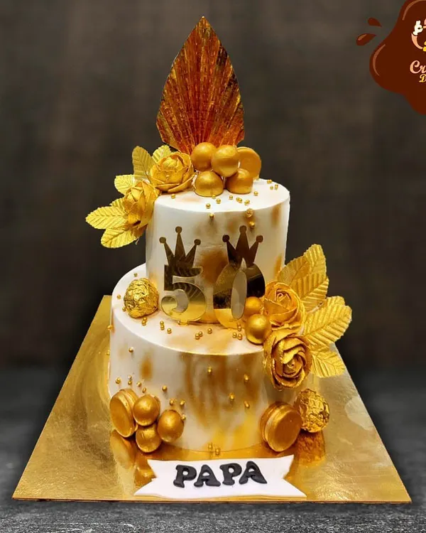 Celebrating a father's 50th birthday is a golden moment. This two-tier cake is adorned with gold flowers, macarons, and crowns, making it a fitting tribute for a "Papa" on his golden jubilee.