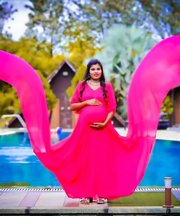 This vibrant pink flying gown is perfect for a poolside maternity shoot. The long, flowing fabric creates a beautiful effect in photos, making it one of my most popular maternity dress rentals in Bangalore.