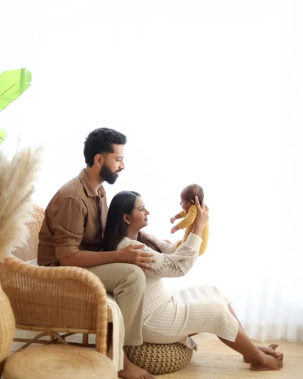 A bright, airy studio portrait of new parents lovingly admiring their newborn baby. This style of family newborn photography focuses on the connection and joy of welcoming a new member to the family.