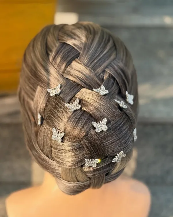 This intricate basket-weave bun is a testament to the advanced skills taught in our hairstyling course. We focus on creating clean, precise patterns and adding delicate accessories like these butterfly clips for a fairytale finish.
