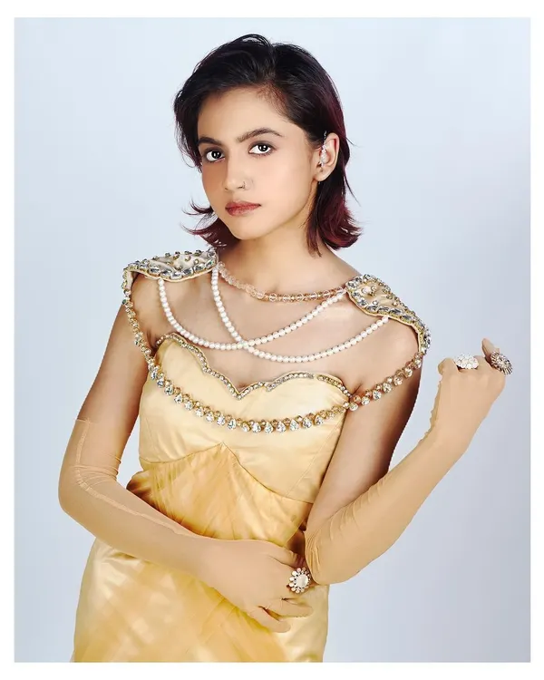 This portrait highlights a beautiful pearl and crystal-embellished bodice on a golden gown. The soft, high-key lighting creates a dreamy and ethereal feel, perfect for showcasing delicate designer work.