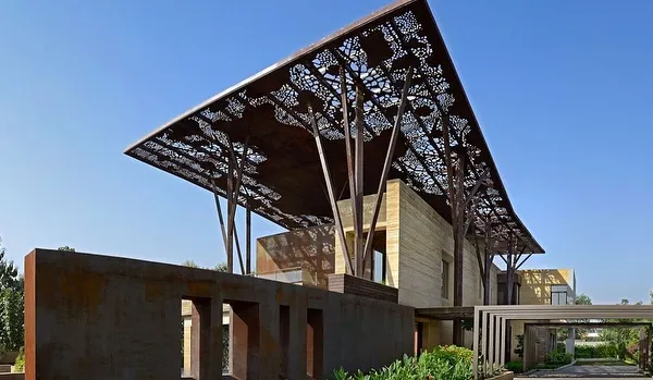 The Tree House in Delhi is defined by its massive, sheltering roof canopy, which is supported by columns that branch out like trees. This award-winning project is a bold statement on integrating natural forms into contemporary urban architecture.
