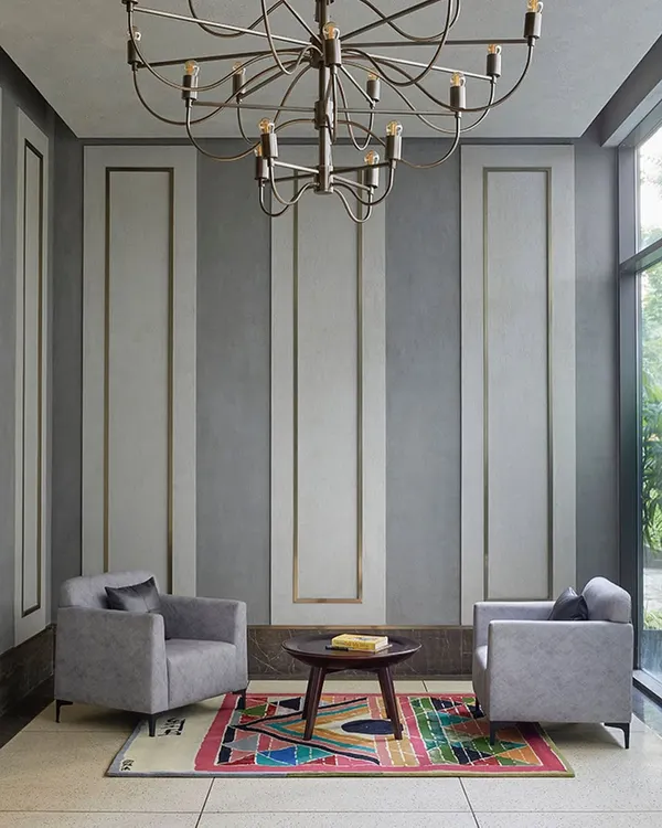 The entrance lobby for the theater and banquet at Rustomjee Elements. The design has a subtle old-world charm with contemporary touches, featuring a unique chandelier and paneled walls that set a tone of understated luxury.