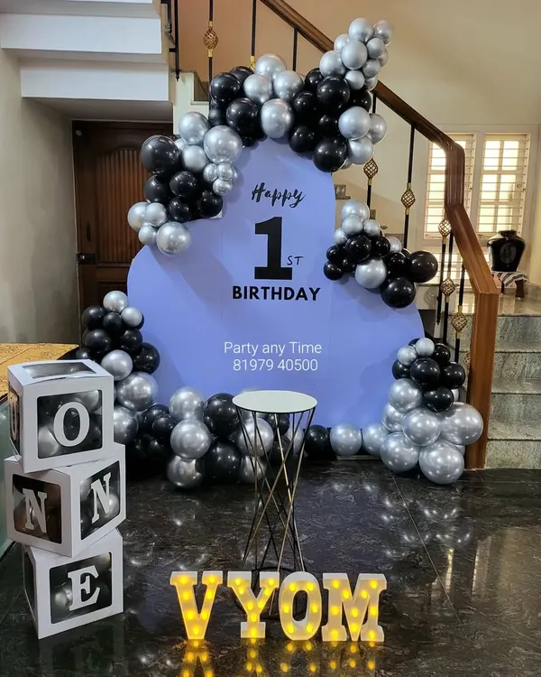 A stylish and modern setup for a first birthday. The black and silver chrome balloons with a simple lavender backdrop create a chic look for this important milestone.