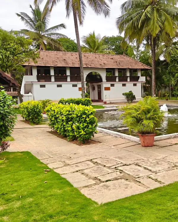 A view of our lush campus with a heritage building overlooking a serene pond. The manicured lawns and stone pathways invite you for a peaceful walk to connect with nature.