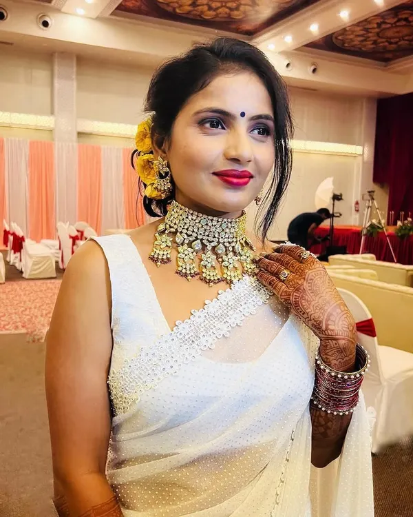 My client was the star of her sister's reception in this stunning white saree. I created a glamorous look with a purple smokey eye, a bold red lip, and a chic floral bun.