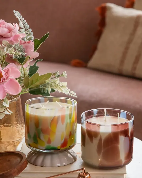 Our commitment is to accessible luxury. Here, our colorful three-wick candle and its more subdued counterpart sit side-by-side, both crafted from 100% natural soy wax and phthalate-free oils for a clean, sustainable burn.