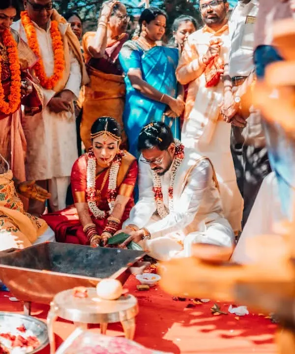 A candid moment from a traditional South Indian wedding ceremony, with the couple surrounded by their family and vibrant rituals.