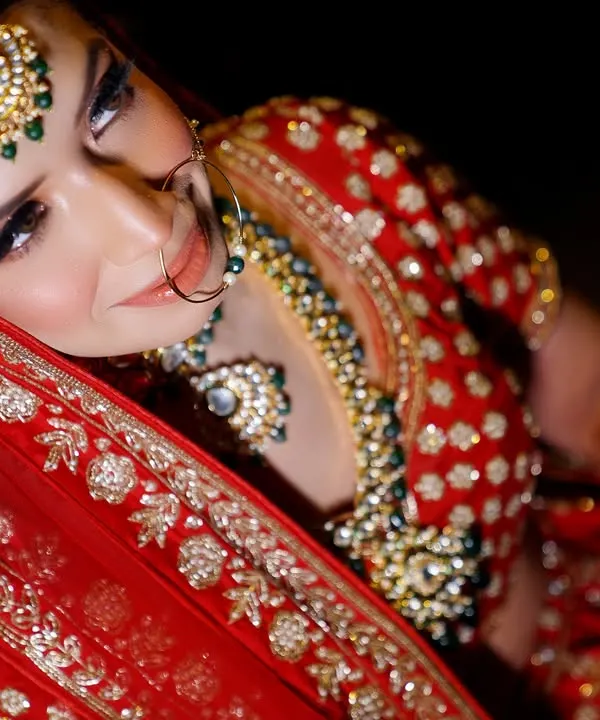A stunning high-angle shot of the bride in her traditional red lehenga. This artistic portrait captures her beauty and the richness of her attire.