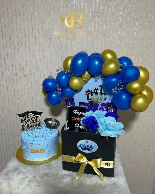 A grand gesture for the best dad. This set includes a custom-decorated cake and a large hamper box filled with chocolates, topped with a blue and gold balloon arch.