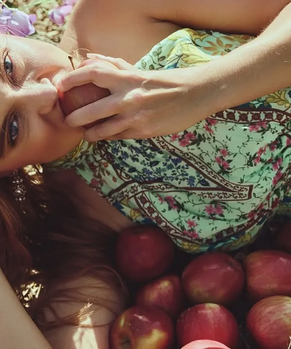 A fashion portrait set in nature. The model is surrounded by apples, creating a soft, almost painterly scene. The warm, natural light and the organic props give this shot a completely different feel from my usual high-contrast work.