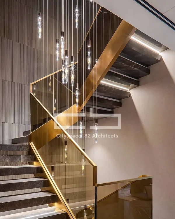 Craftsmanship is at the heart of our work. This modern staircase combines sleek dark marble, elegant glass railings with gold accents, and a striking chandelier, turning a functional element into a sculptural centerpiece.