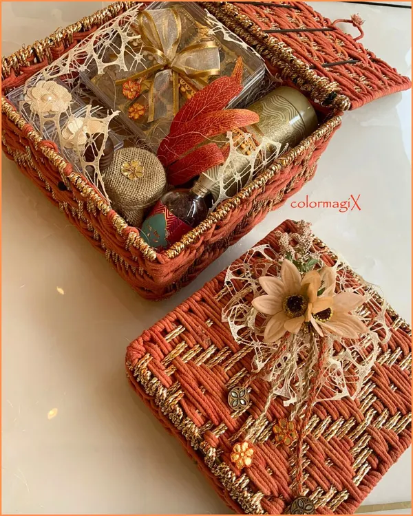 Our customizable jute hampers are a blend of eco-luxury and personal style. This orange woven box is filled with treats and adorned with a delicate flower, showcasing a rustic yet chic aesthetic.