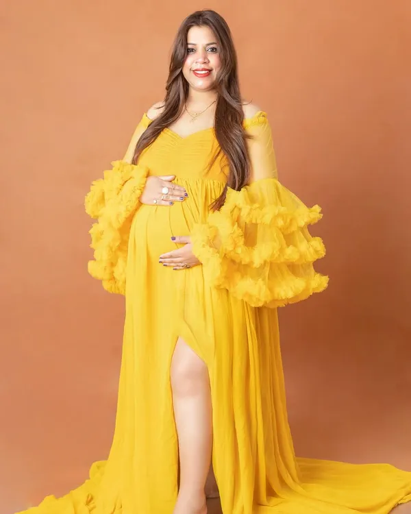 Our vibrant yellow gown with dramatic ruffled sleeves is a showstopper. It’s perfect for moms who want a bold and cheerful look for their studio maternity photos.