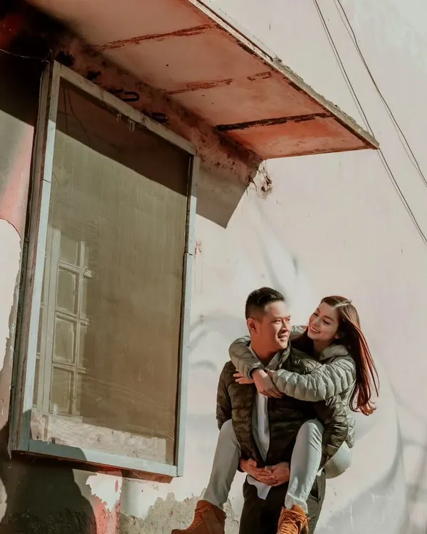 A playful piggyback ride against a rustic, artistic wall in Delhi. This shot captures the fun and candid moments we find while exploring new cities for destination pre-wedding shoots.