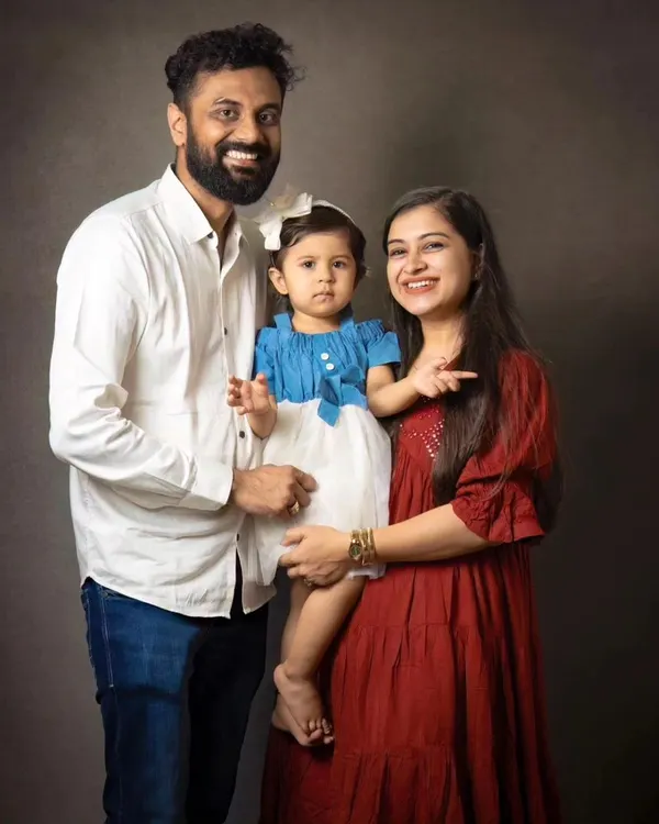 A classic family portrait that never goes out of style. The simple, dark backdrop ensures that the focus remains on the family's happy expressions and connection.