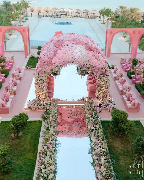An aerial view of the 'Echoes of Pink' wedding in Doha. The entire space, from the architectural arches to the seating, was designed in monochromatic shades of pink, creating a stunning visual against the poolside venue. The floral mandap stands as the beautiful centerpiece.